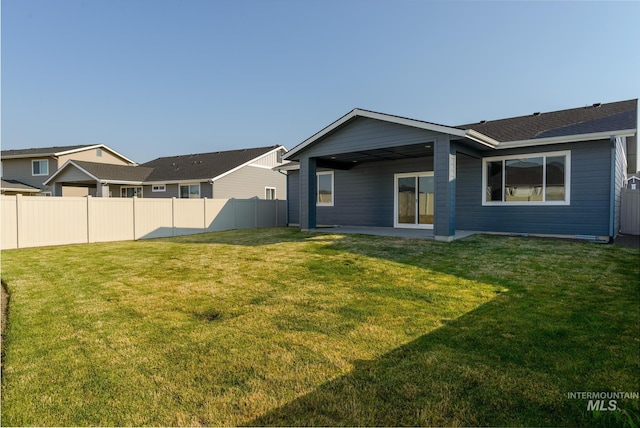 rear view of property with a lawn and fence