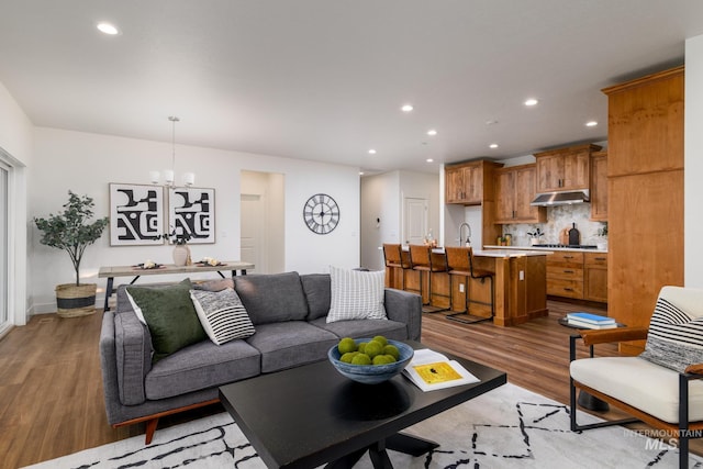 living room with light wood finished floors, recessed lighting, and an inviting chandelier