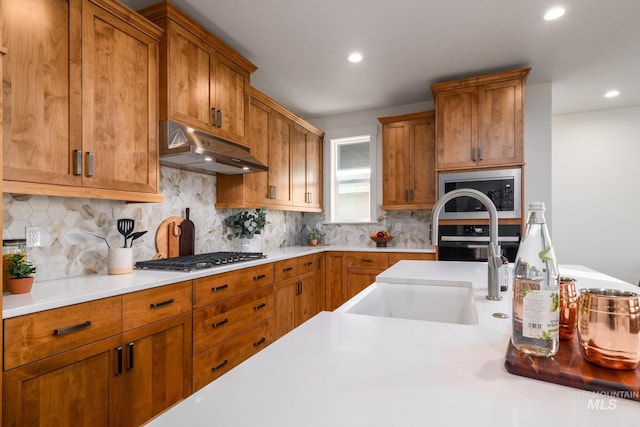 kitchen with stainless steel gas cooktop, built in microwave, a sink, light countertops, and under cabinet range hood