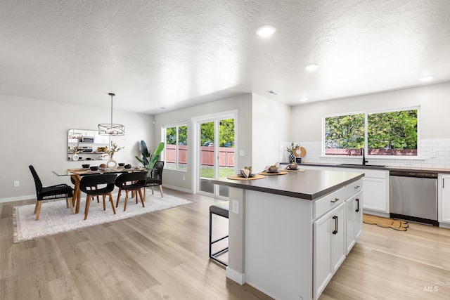 19920 Lenape Ct, Caldwell, ID 83605 - kitchen with dishwasher, dark countertops, a sink, light wood-style floors, and a textured ceiling