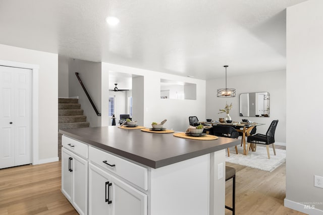 19920 Lenape Ct, Caldwell, ID 83605 - kitchen with dark countertops, white cabinets, light wood finished floors, a kitchen island, and baseboards