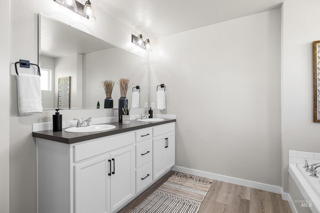 19920 Lenape Ct, Caldwell, ID 83605 - bathroom featuring double vanity, a garden tub, wood finished floors, and baseboards
