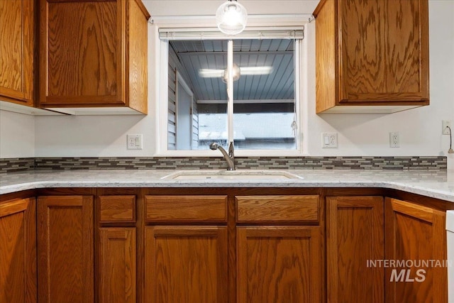 kitchen featuring light stone countertops, sink, and decorative backsplash