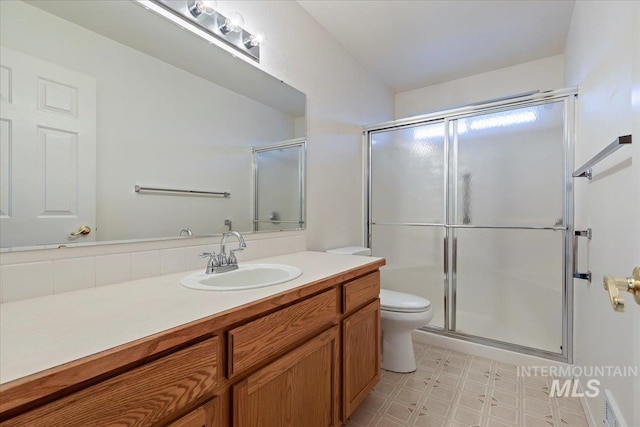 bathroom with vanity, toilet, and an enclosed shower