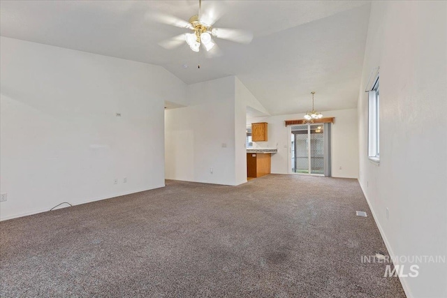 unfurnished living room with lofted ceiling, ceiling fan with notable chandelier, and carpet floors