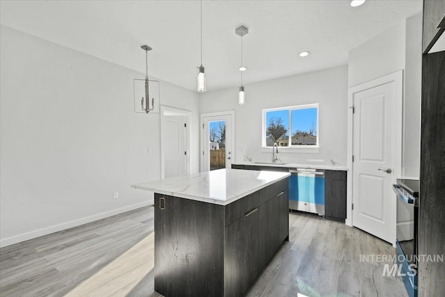 kitchen with stainless steel dishwasher, sink, a kitchen island, light wood-type flooring, and decorative light fixtures