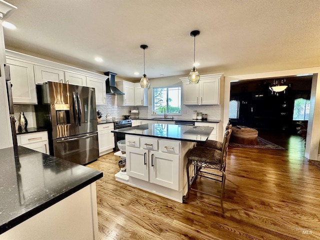 3195 N 3526e, Kimberly, ID 83341 - kitchen with wall chimney exhaust hood, dark countertops, stainless steel fridge, light wood-style floors, and white cabinets