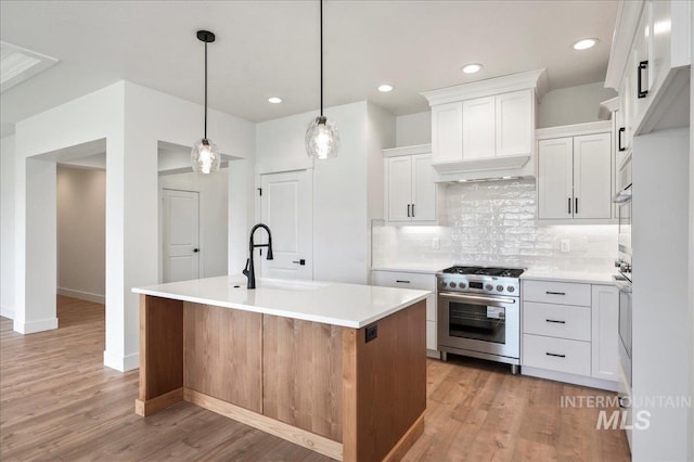 kitchen with white cabinets, sink, appliances with stainless steel finishes, and an island with sink