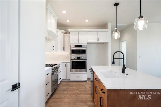 kitchen featuring pendant lighting, sink, white cabinets, and stainless steel appliances