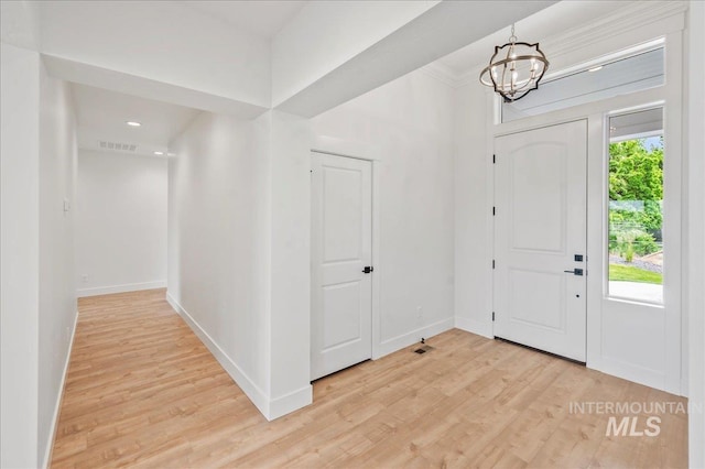 entrance foyer featuring light hardwood / wood-style flooring, a wealth of natural light, and a chandelier