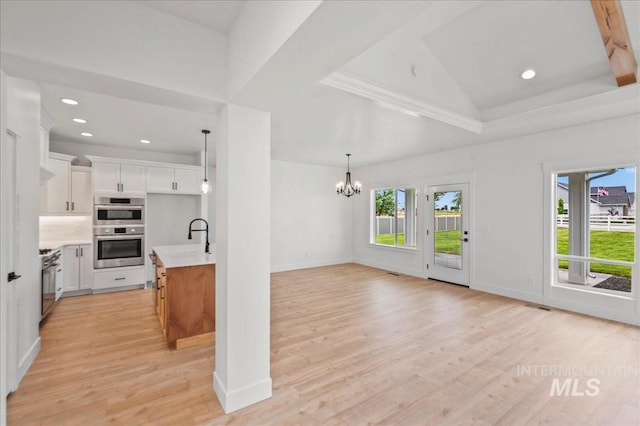 unfurnished living room with a chandelier, light wood-type flooring, vaulted ceiling, and sink