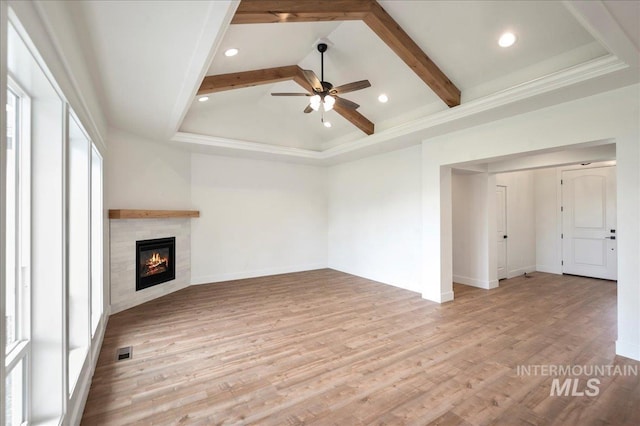 unfurnished living room featuring a fireplace, beam ceiling, light hardwood / wood-style flooring, and ceiling fan