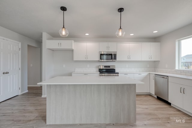 16888 Dunning Way, Caldwell, ID 83607 - kitchen with a center island, light wood-style floors, stainless steel appliances, light countertops, and white cabinetry