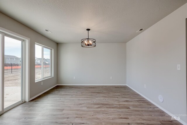 16888 Dunning Way, Caldwell, ID 83607 - spare room with a chandelier, a textured ceiling, light wood-style flooring, and visible vents