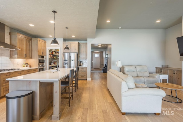 11706 W Lilium St, Star, ID 83669 - kitchen with stainless steel appliances, a breakfast bar, decorative backsplash, open floor plan, and light wood finished floors