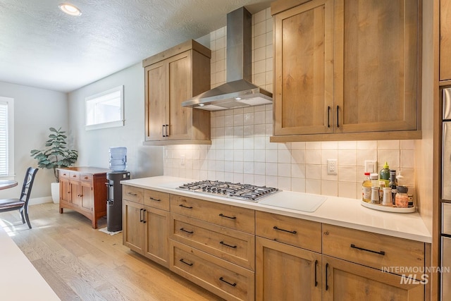 11706 W Lilium St, Star, ID 83669 - kitchen with wall chimney range hood, light wood finished floors, light countertops, decorative backsplash, and a textured ceiling