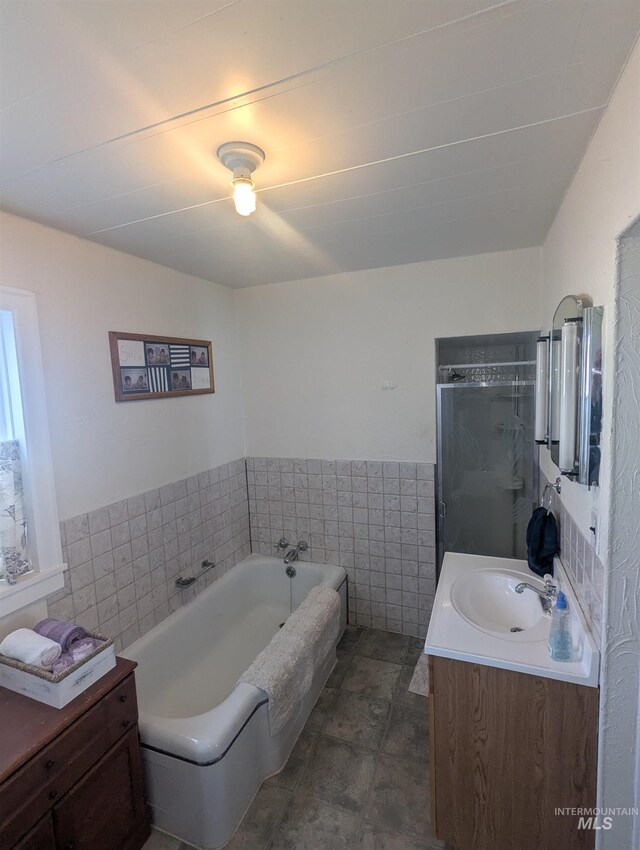 231 Willow Ave E, Fairfield, ID 83327 - full bath featuring vanity, wainscoting, tile walls, a bath, and a shower stall