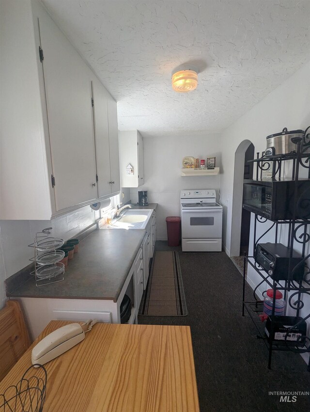231 Willow Ave E, Fairfield, ID 83327 - kitchen featuring a textured ceiling, arched walkways, white range with electric cooktop, a sink, and white cabinetry