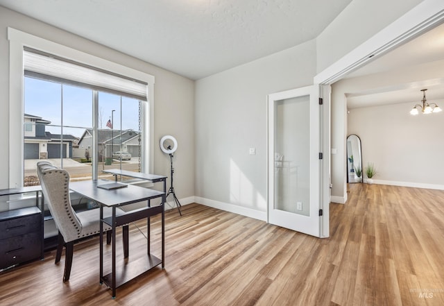 dining area with an inviting chandelier, baseboards, and light wood-type flooring