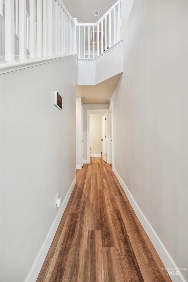 corridor featuring a high ceiling, wood finished floors, and baseboards