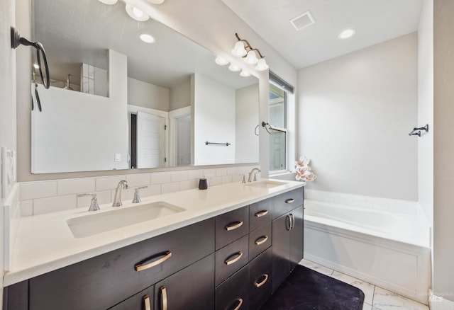 bathroom featuring a garden tub, visible vents, marble finish floor, and a sink