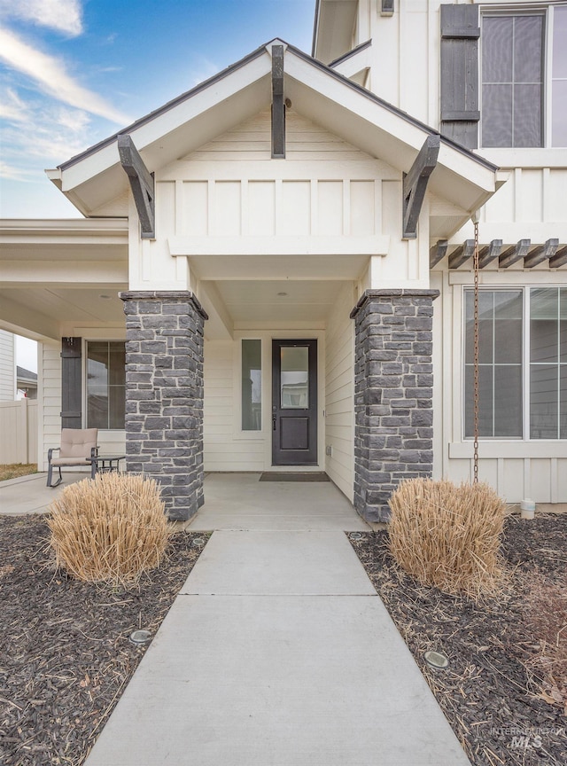 entrance to property with stone siding, covered porch, and board and batten siding