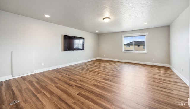 unfurnished room with recessed lighting, wood finished floors, baseboards, and a textured ceiling