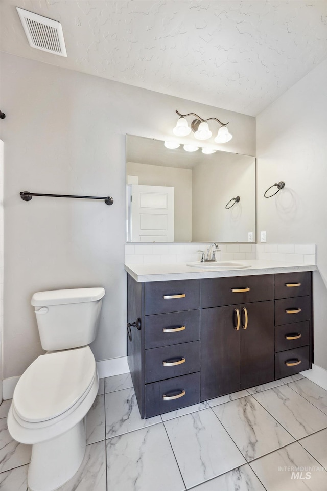 bathroom featuring vanity, toilet, visible vents, and marble finish floor