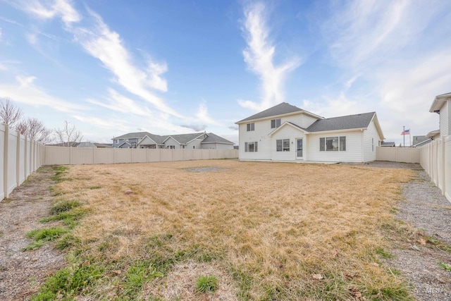 rear view of house with a yard and a fenced backyard