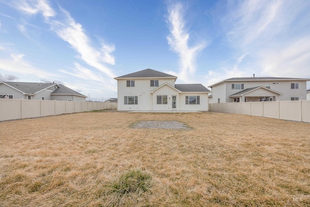 rear view of house featuring a lawn and a fenced backyard