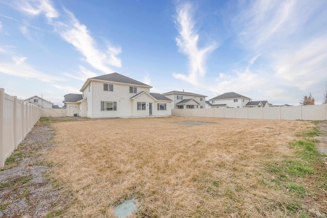 rear view of property featuring a yard and a fenced backyard