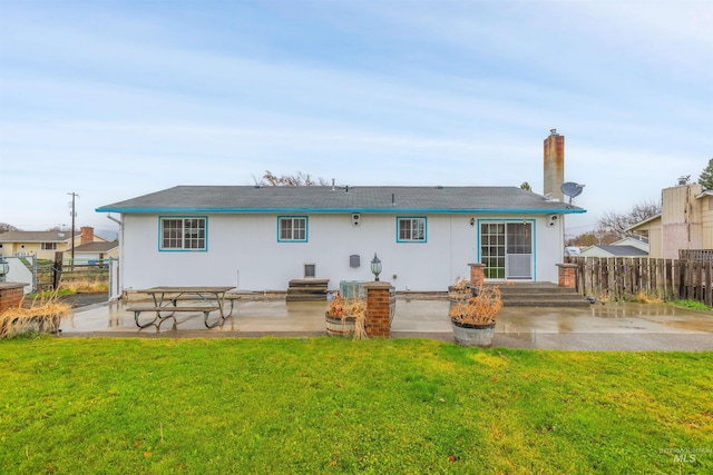 back of property featuring a patio area and a lawn