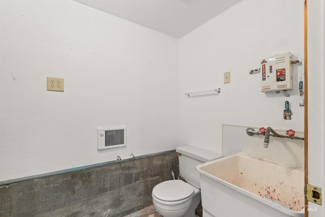 bathroom with heating unit, sink, and toilet