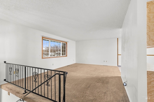 carpeted empty room with a textured ceiling