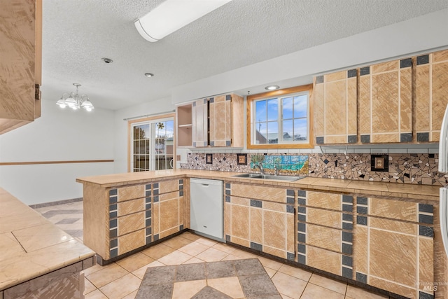 kitchen with decorative light fixtures, white dishwasher, a healthy amount of sunlight, and sink