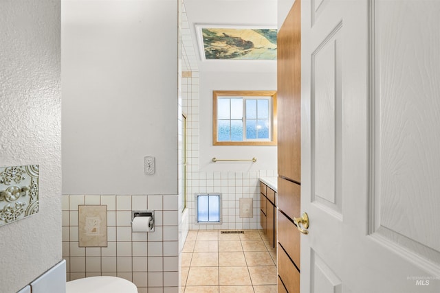 bathroom with tile patterned flooring, toilet, and tile walls