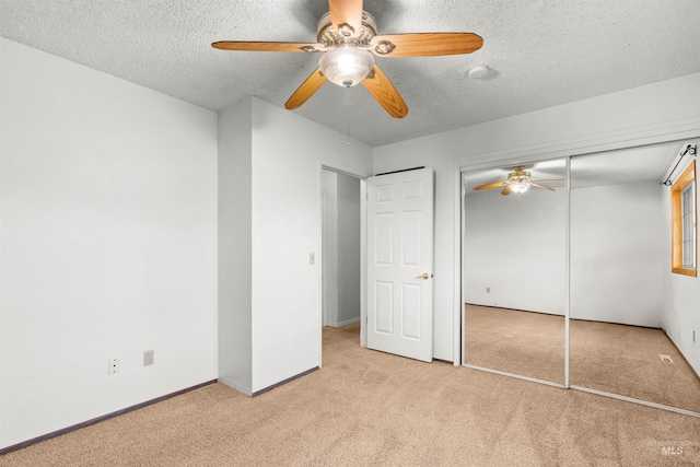 unfurnished bedroom with light carpet, a textured ceiling, a closet, and ceiling fan