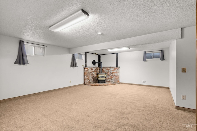 basement featuring carpet, a textured ceiling, and a wood stove