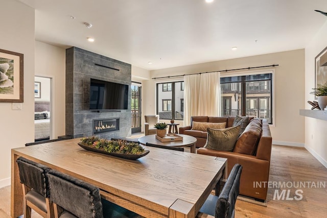 dining area with a tiled fireplace and light wood-type flooring