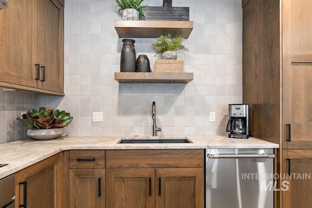 kitchen with tasteful backsplash, stainless steel dishwasher, light stone countertops, and sink