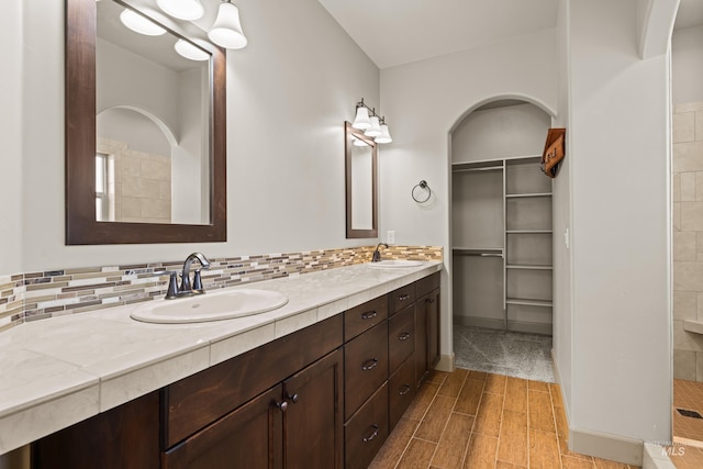 168 S Tresa Ave, Star, ID 83669 - bathroom featuring double vanity, a tile shower, tasteful backsplash, a walk in closet, and wood finished floors