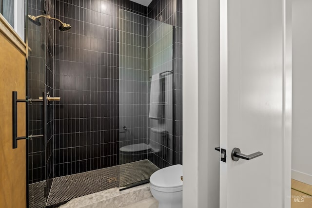 bathroom with a shower with shower door and toilet