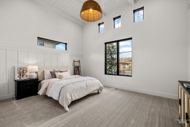 bedroom with a high ceiling, beamed ceiling, and carpet