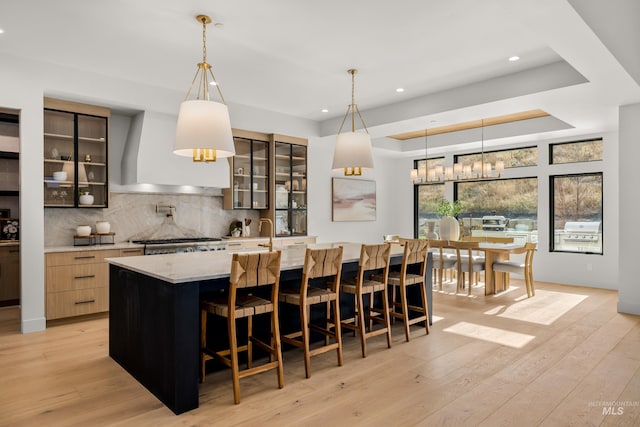 kitchen with a large island with sink, decorative light fixtures, and light hardwood / wood-style flooring