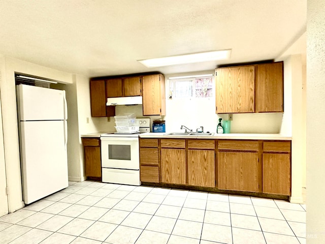 kitchen featuring white appliances, sink, light tile patterned floors, and a textured ceiling