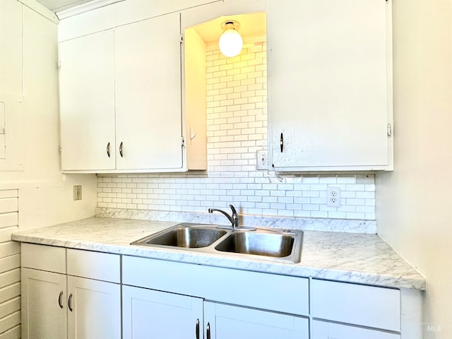 kitchen featuring white cabinetry, sink, light stone counters, and tasteful backsplash