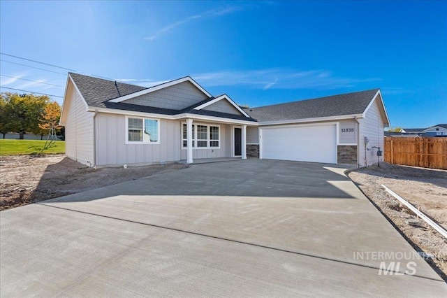 ranch-style home with board and batten siding, a shingled roof, fence, concrete driveway, and an attached garage