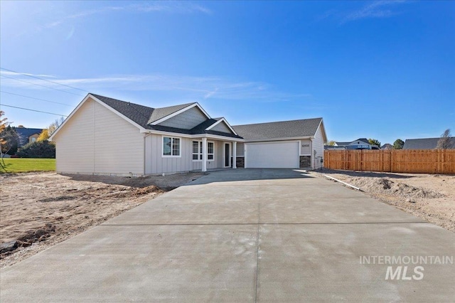 single story home with board and batten siding, fence, a garage, and driveway