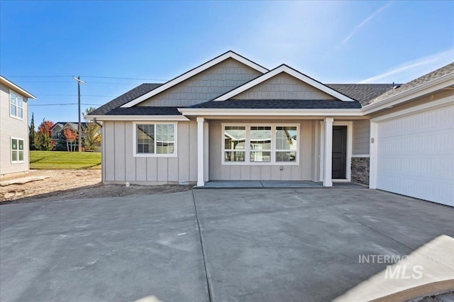 view of front of home featuring a garage, roof with shingles, board and batten siding, and driveway