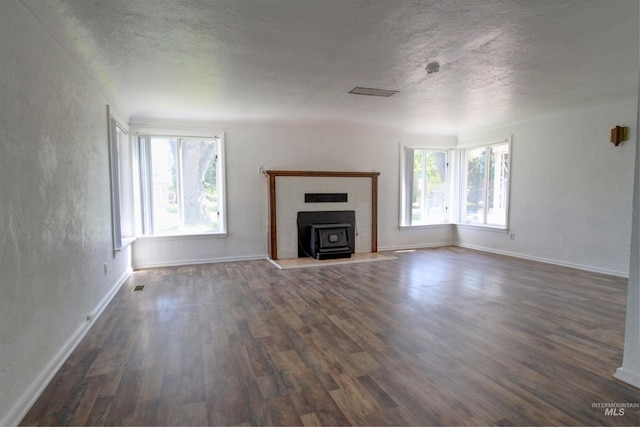 2912 S Harmony Ave, Boise, ID 83706 - unfurnished living room featuring dark wood finished floors, a textured ceiling, baseboards, and a wood stove
